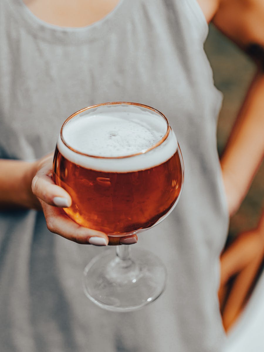 Photographer person holding a large glass of beer with gold rim