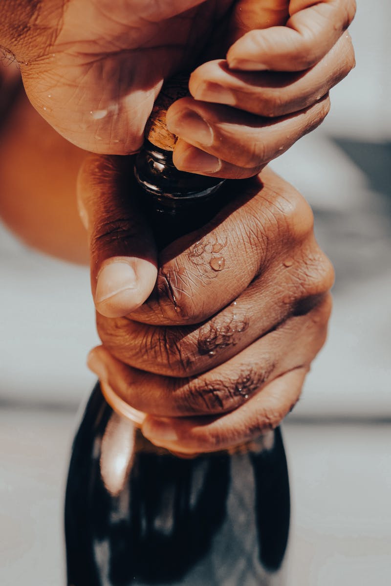 close-up image of person opening a corked beer bottle