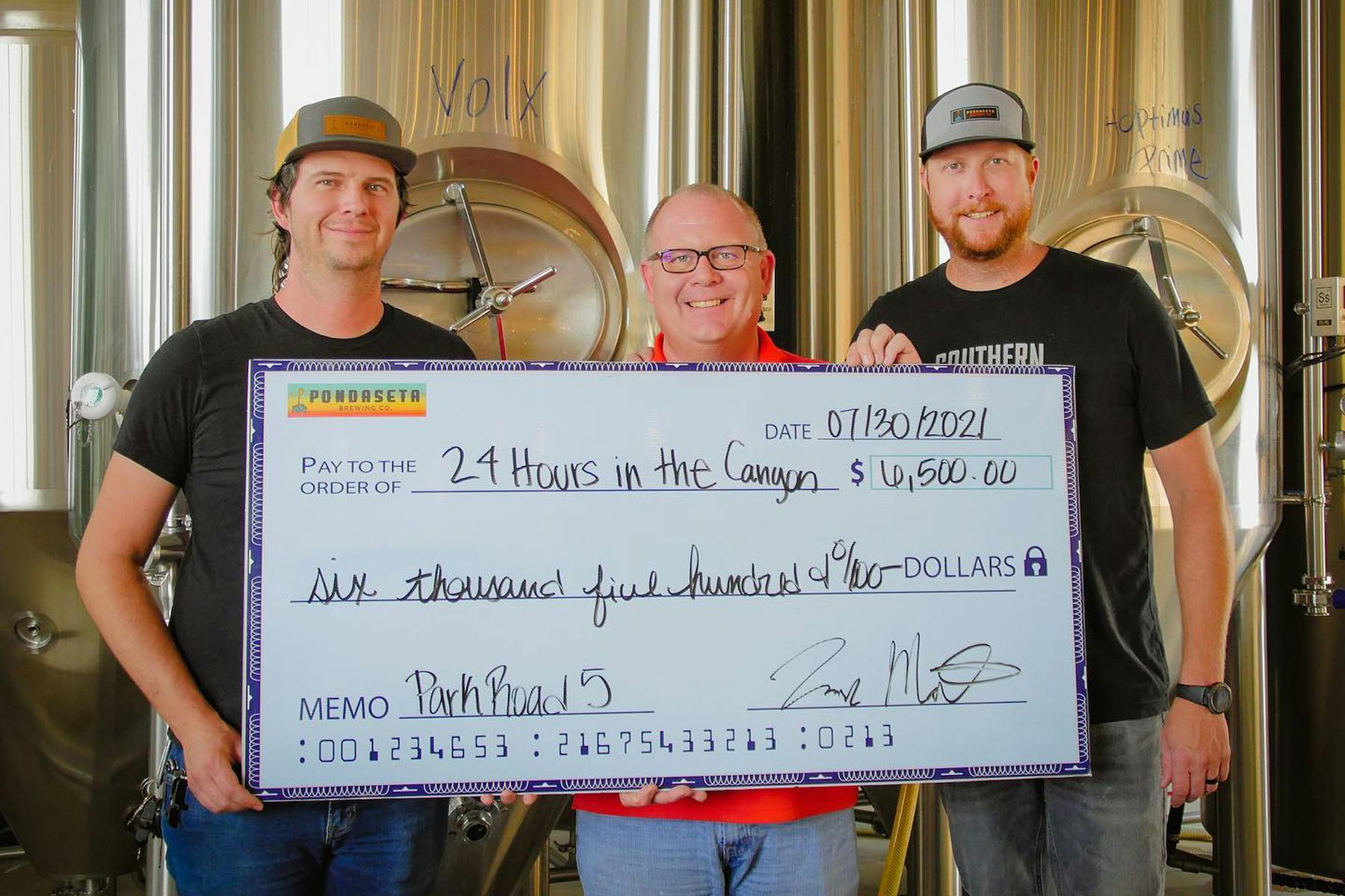 3 Men hold a giant check made out to 24 Hours in the Canyon