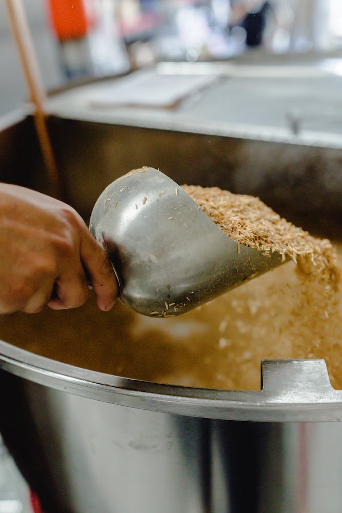 A scoop of grain is added to a beer mash ton