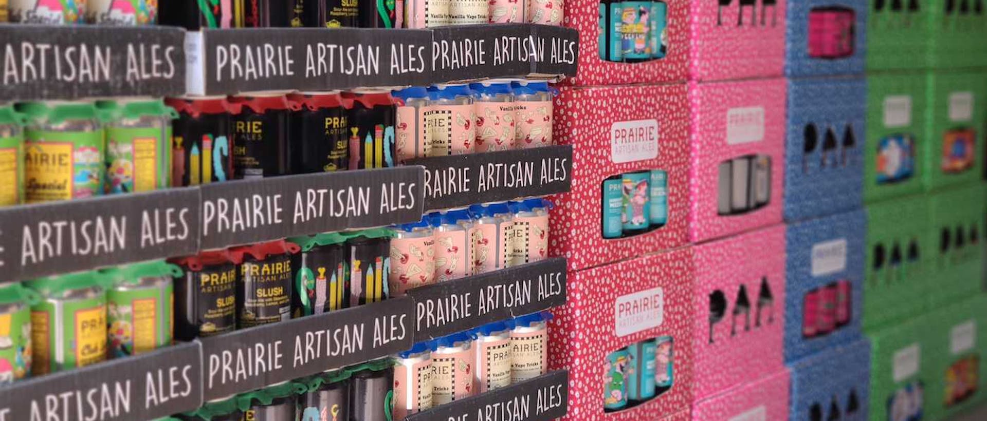 Stacks of colorful Prairie Artisan Ales beer cans in cases and boxes