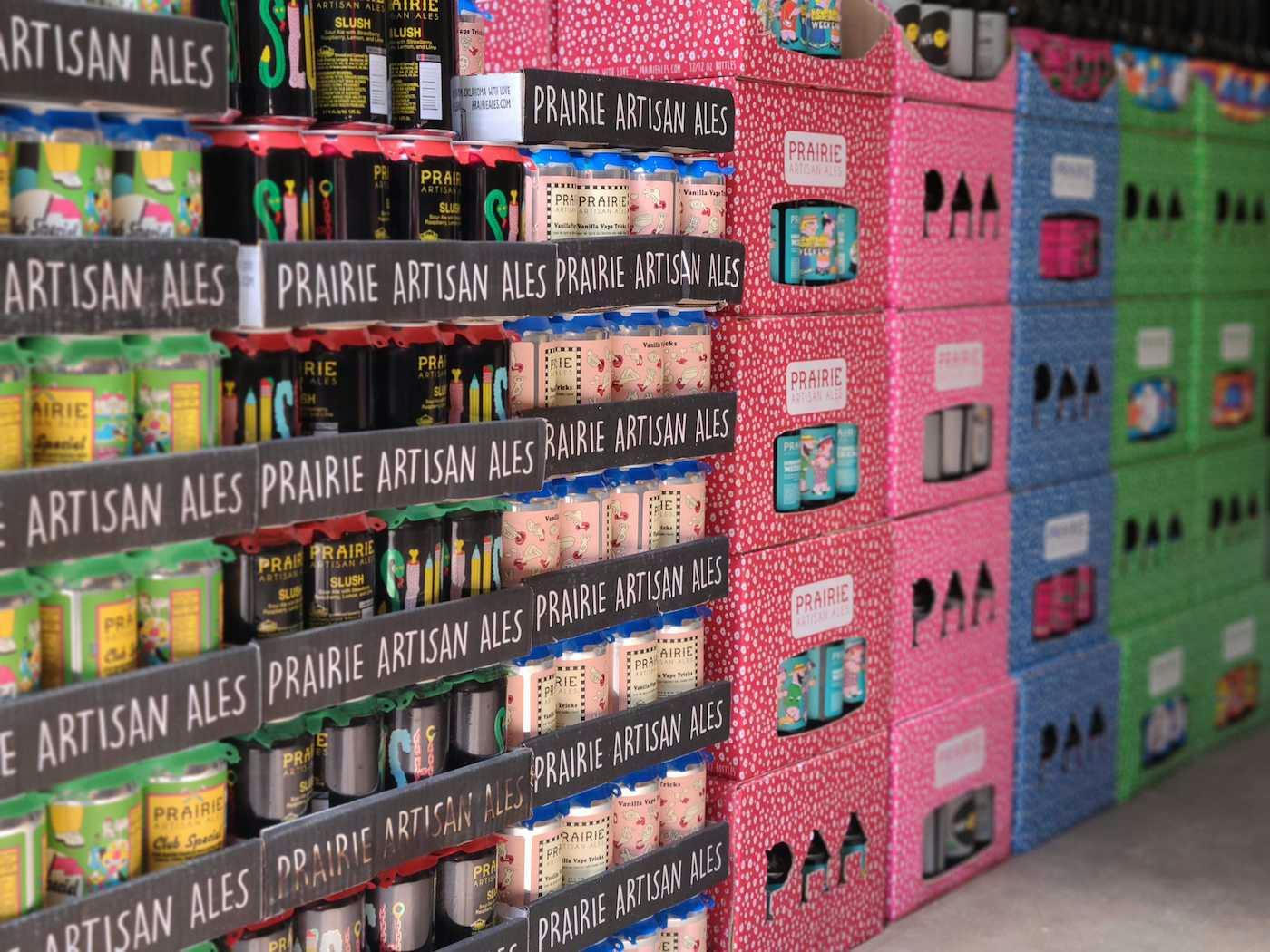 Stacks of colorful Prairie Artisan Ales beer cans in cases and boxes