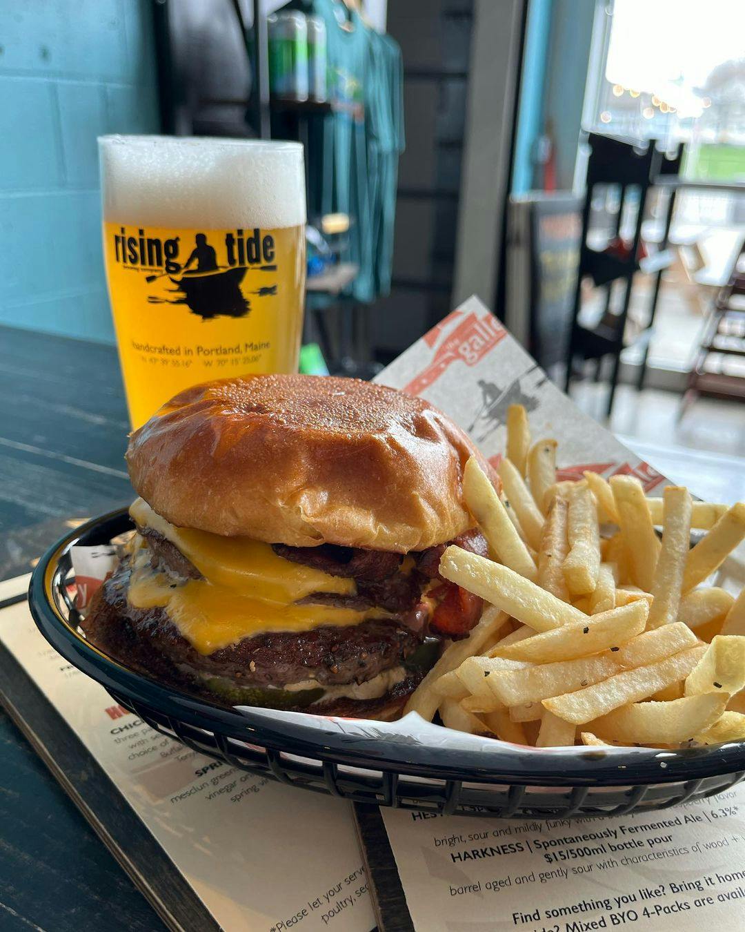 Photo of a double burger and fries with a pint of Rising Tide beer