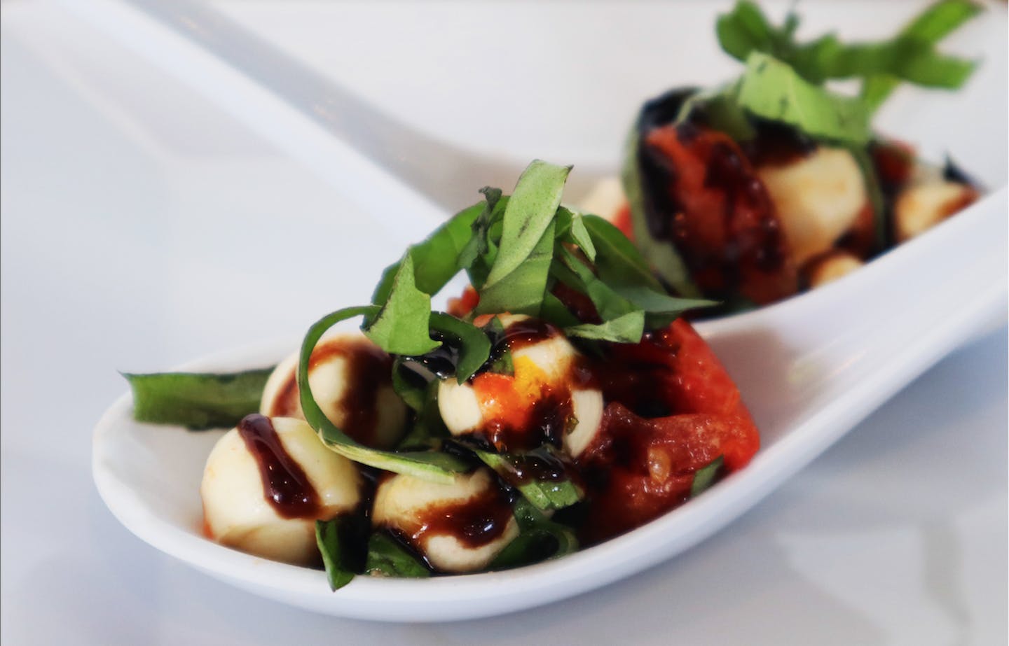 Close up image of caprese salad in two large appetizer spoons