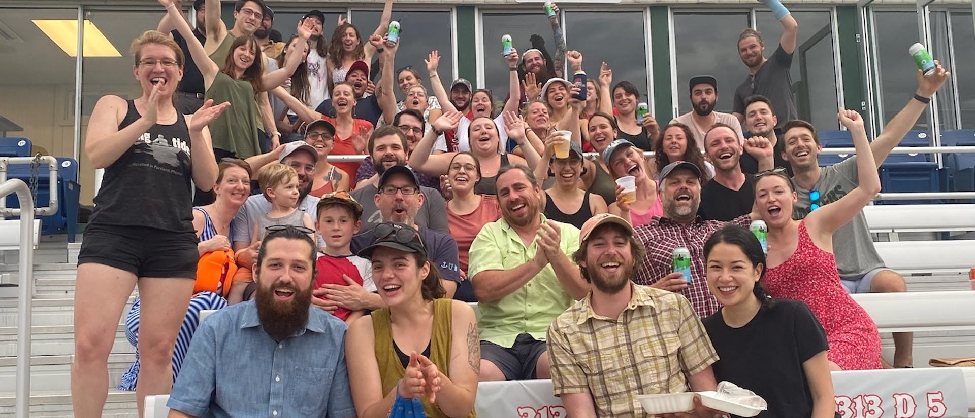 A majority of the Rising Tide staff and their significant others gathered together and cheering at a SeaDogs game.  