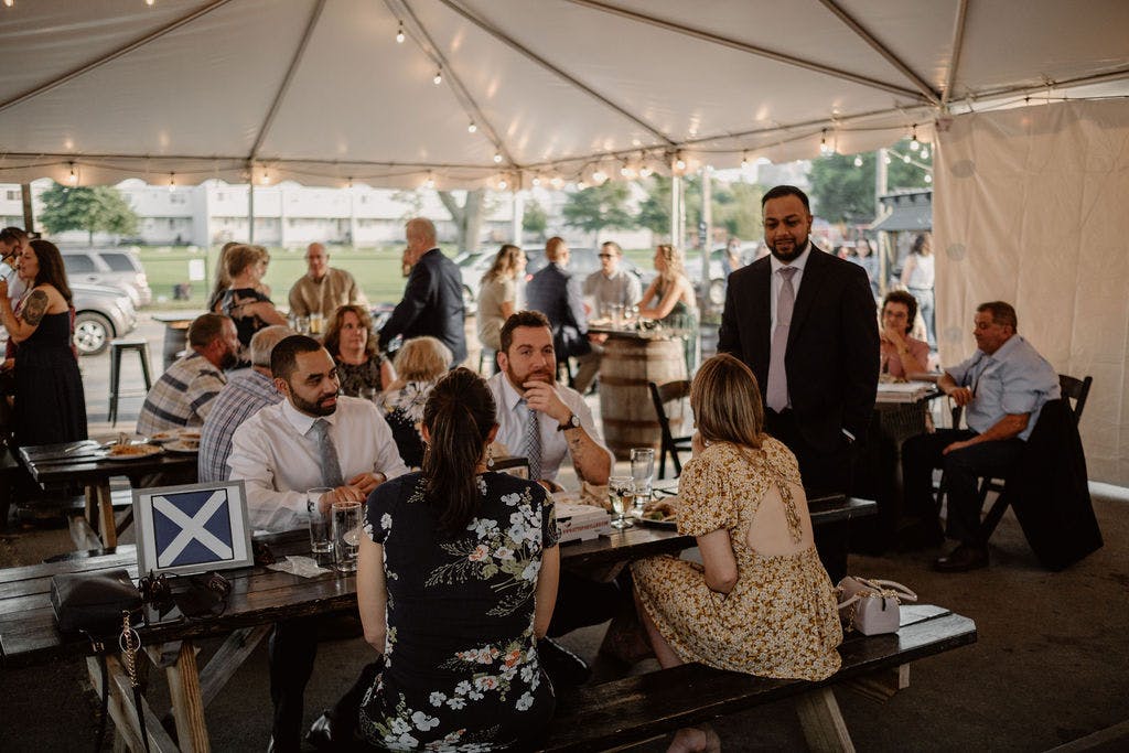 a table of guests during an event under a lit tent. 