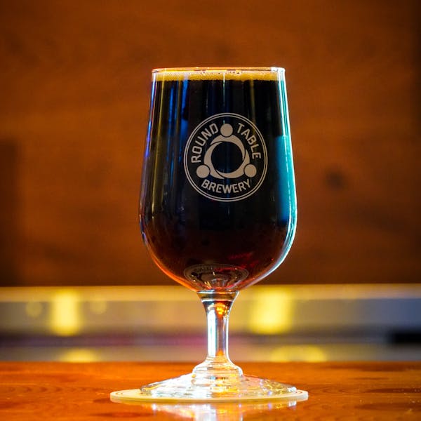 A dark stout beer in a Round Table Brewery glass.