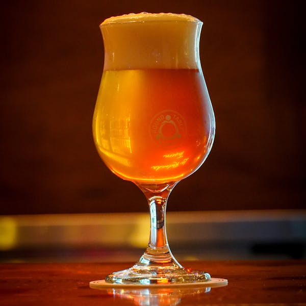 A golden copper colored beer in a Round Table Brewery glass.