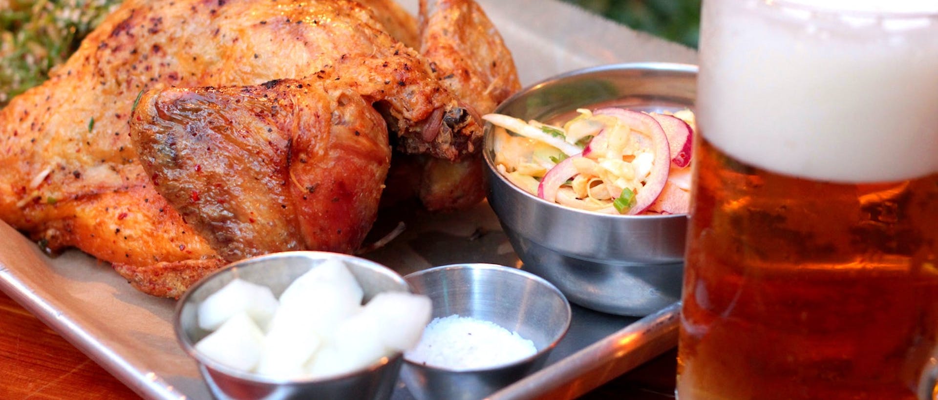 pexels-calvin-lee-9967259 Fully roasted chicken with a side salad on a try next to a beer