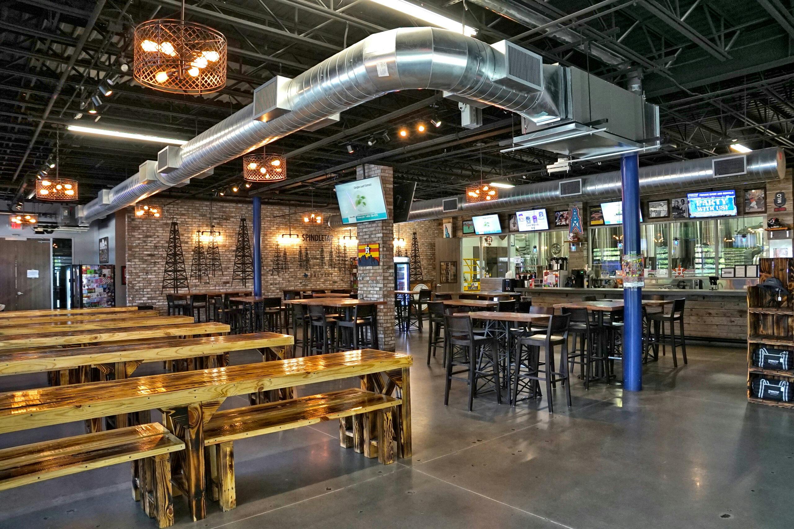 Inside SpindleTap Brewery. Where people sit on benches and tables and enjoy a cold beer.