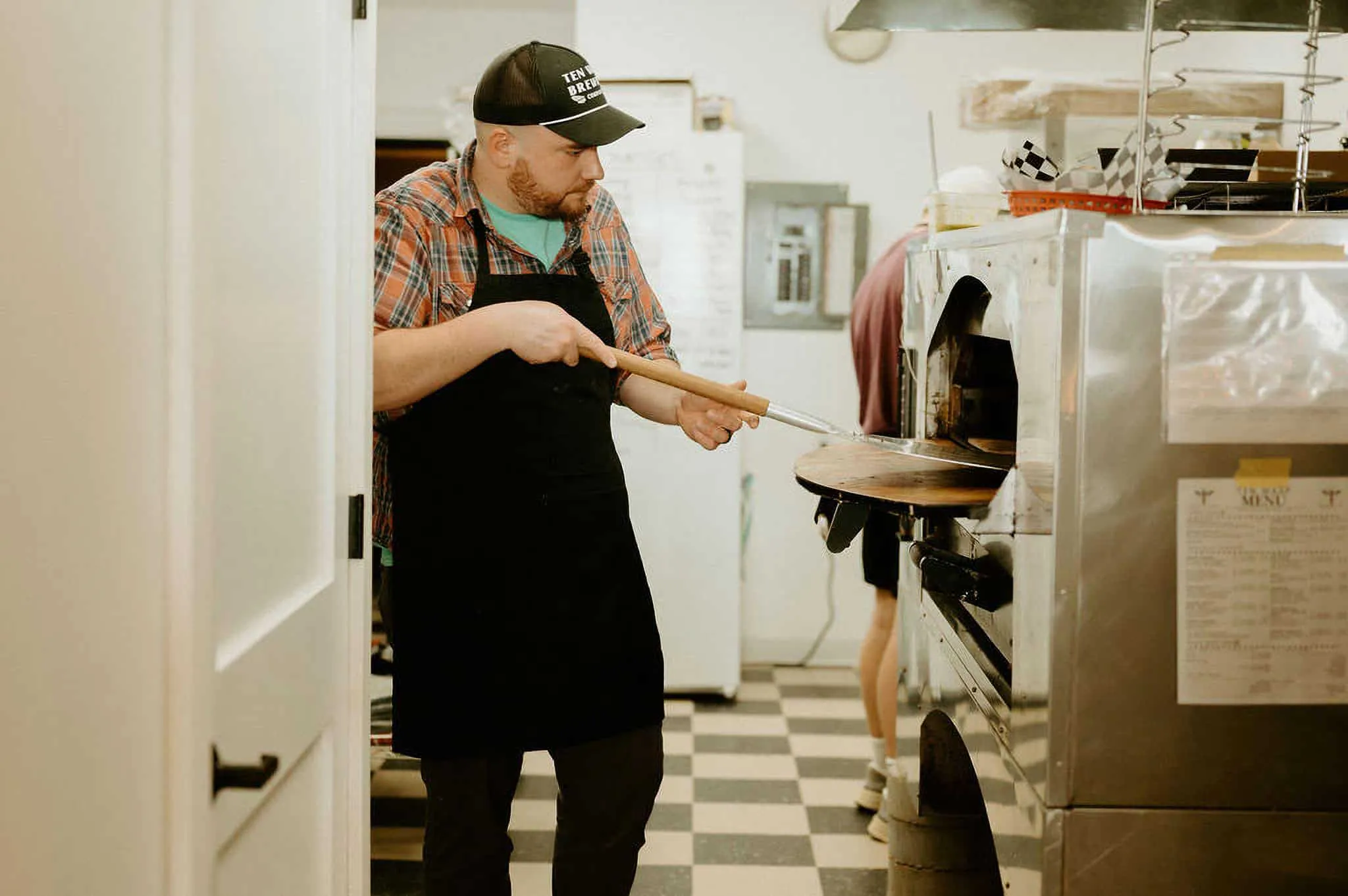 A chef pulls a pizza out of a pizza oven
