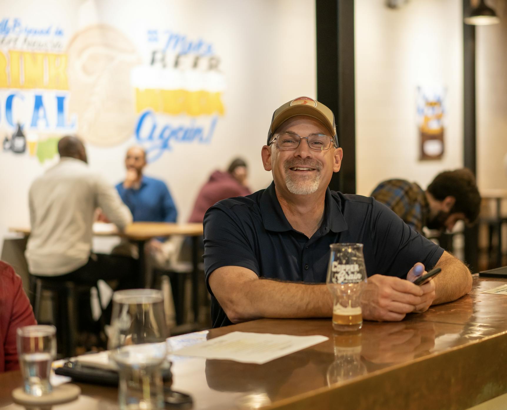 Customer smiling while sitting at the bar having a beer.