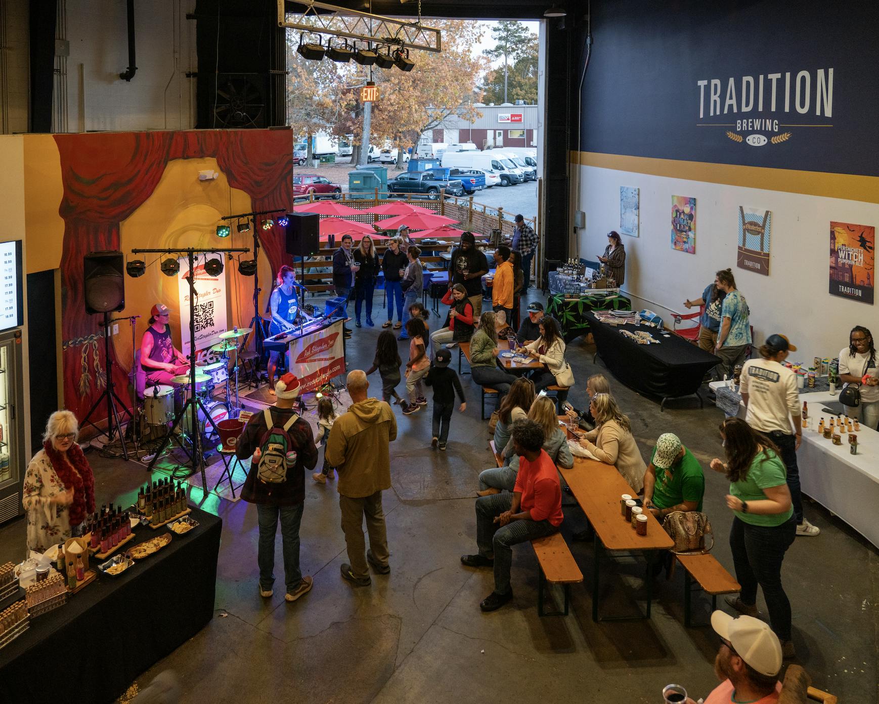Wide shot of the taproom with vendors and a band playing.