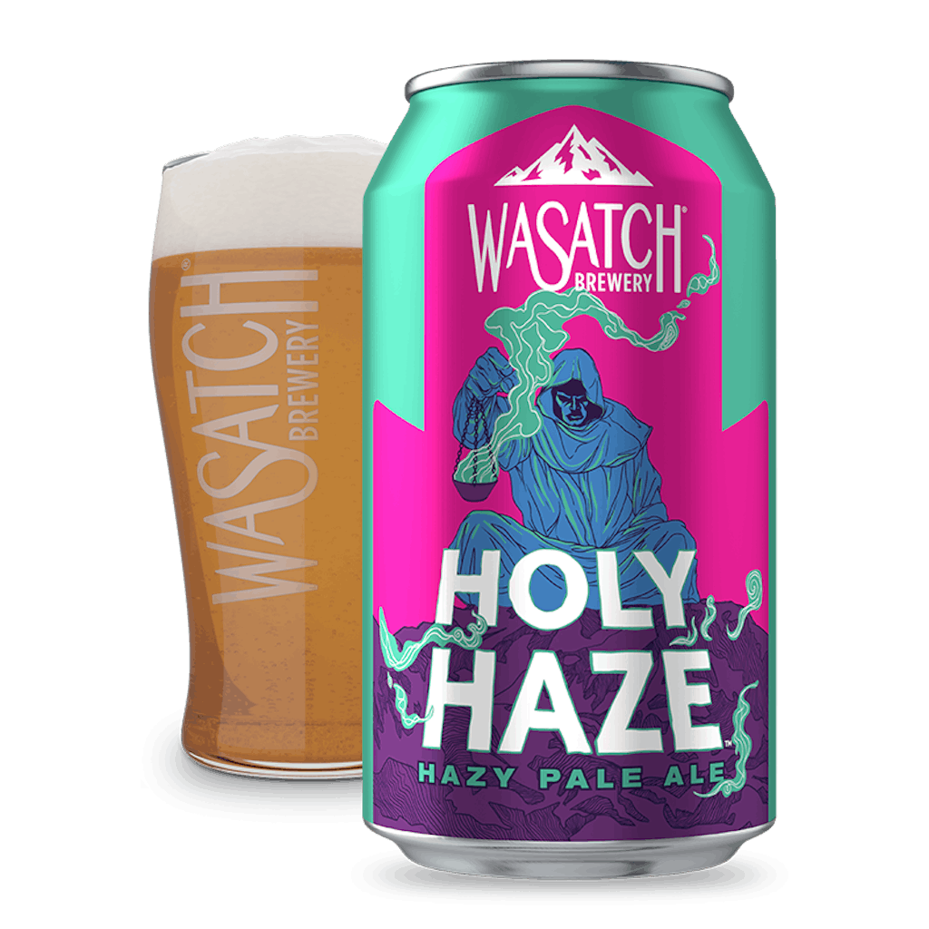Wasatch Brewery's Holy Haze Hazy Pale Ale can in front of a glass of a dark, wheat-colored beer