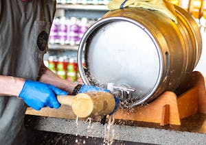 Male Brewer Tapping Firkin