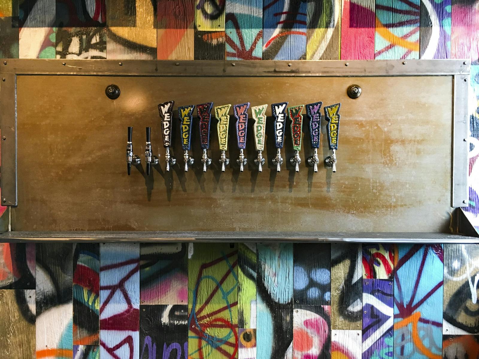 Artistic tap wall with colorful Wedge Brewing tap handles