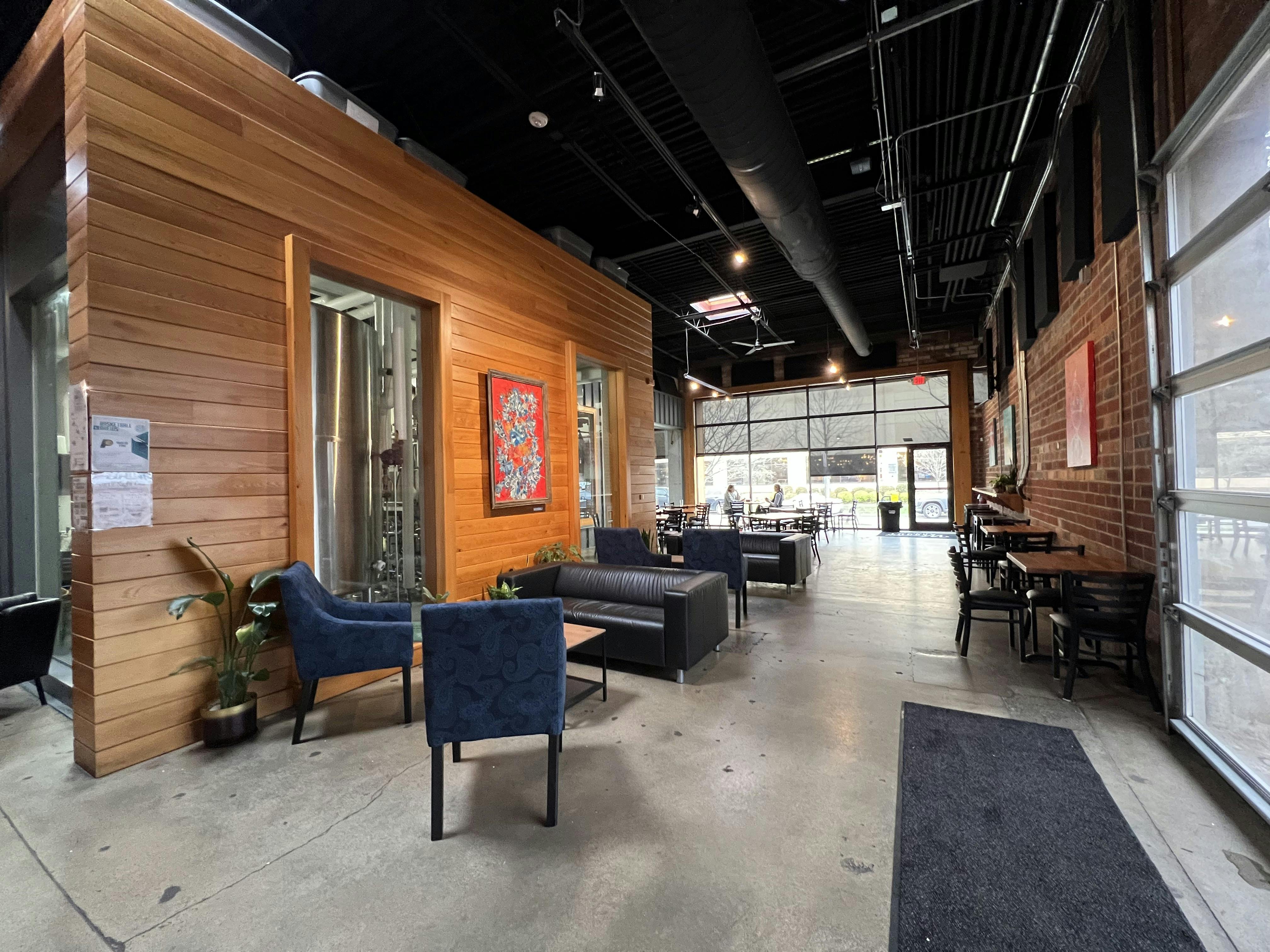 Inside of a coffee bar seating area with a mix of couches, chairs, and tables.