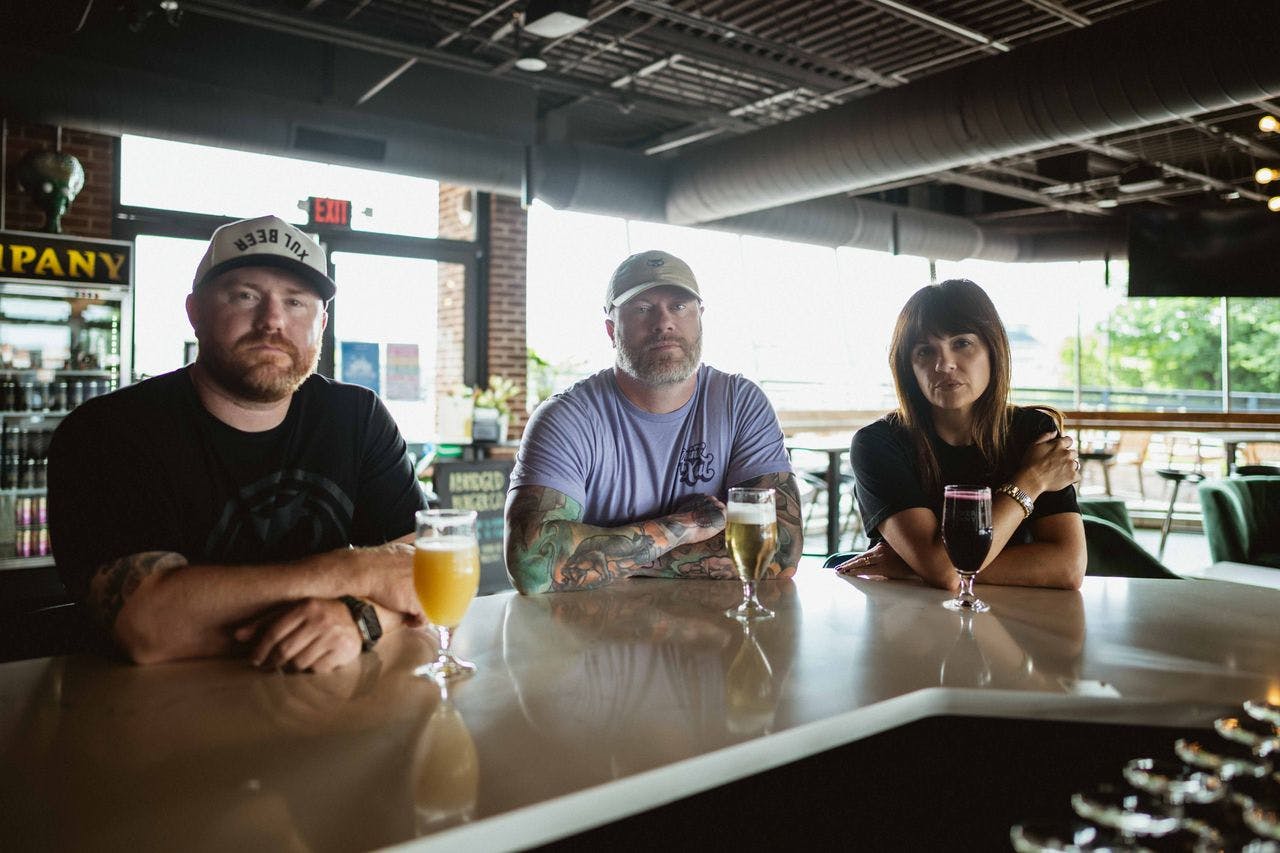Brad, Seth, & Tara sitting at the bar with beers in front of them.