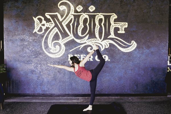 Yoga pose in front of our logo wall in the taproom